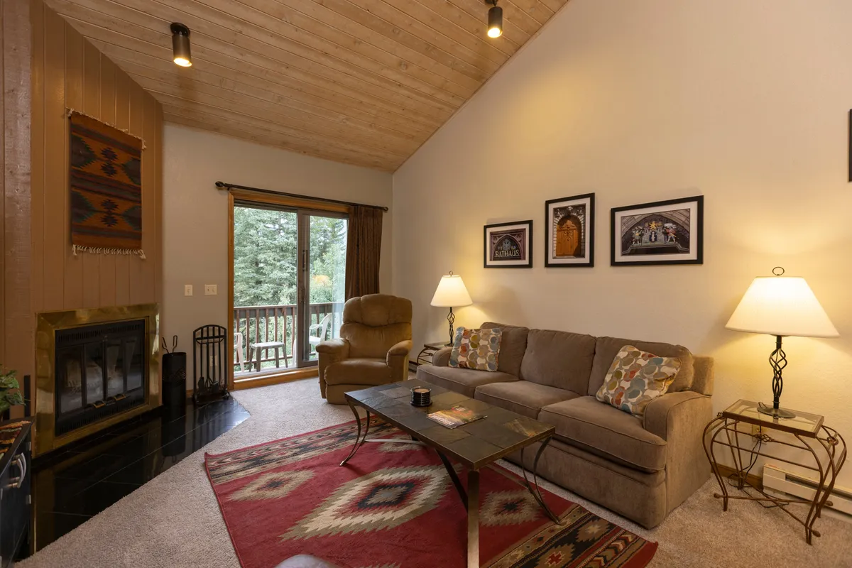 A comfortable living room centered around a plush sofa, coffee table, and a fireplace, with large windows letting in natural light. The setting is perfect for relaxing, sharing stories, and enjoying the warmth after a day of adventure.